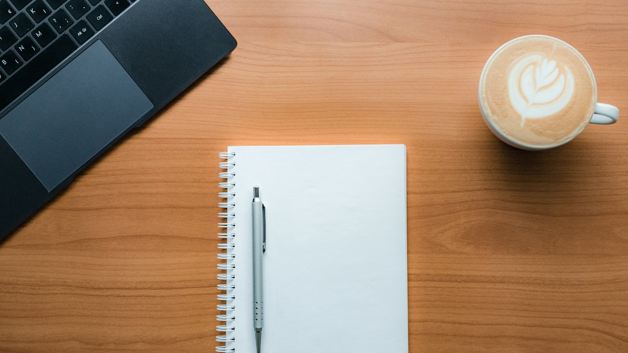 Notizblock, Stift und Kaffee auf einem Holztisch
